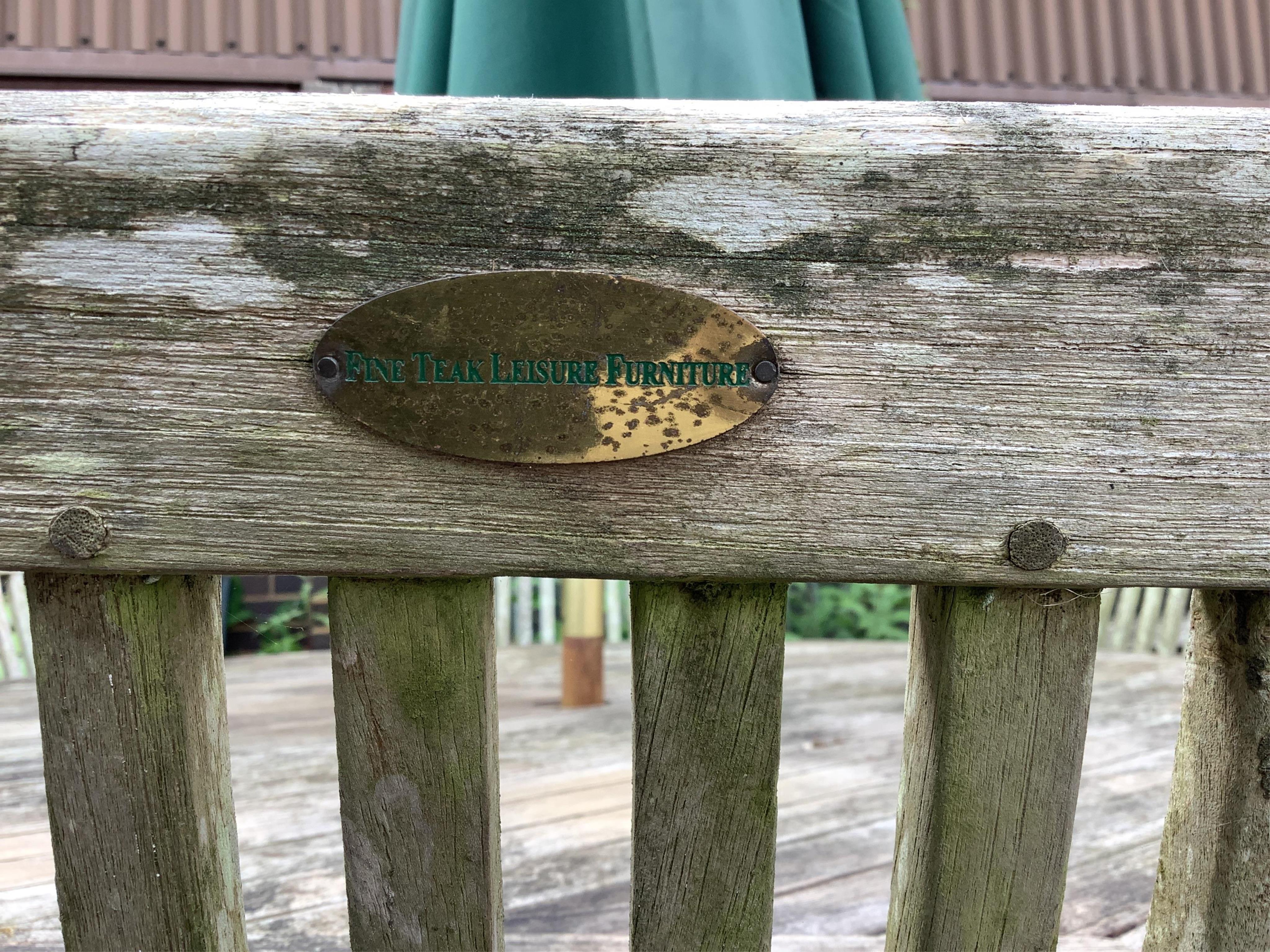 A circular weathered teak garden table, diameter 150cm, height 74cm, together with six teak folding garden chairs, two with arms and a green canvas crank parasol. Condition - fair